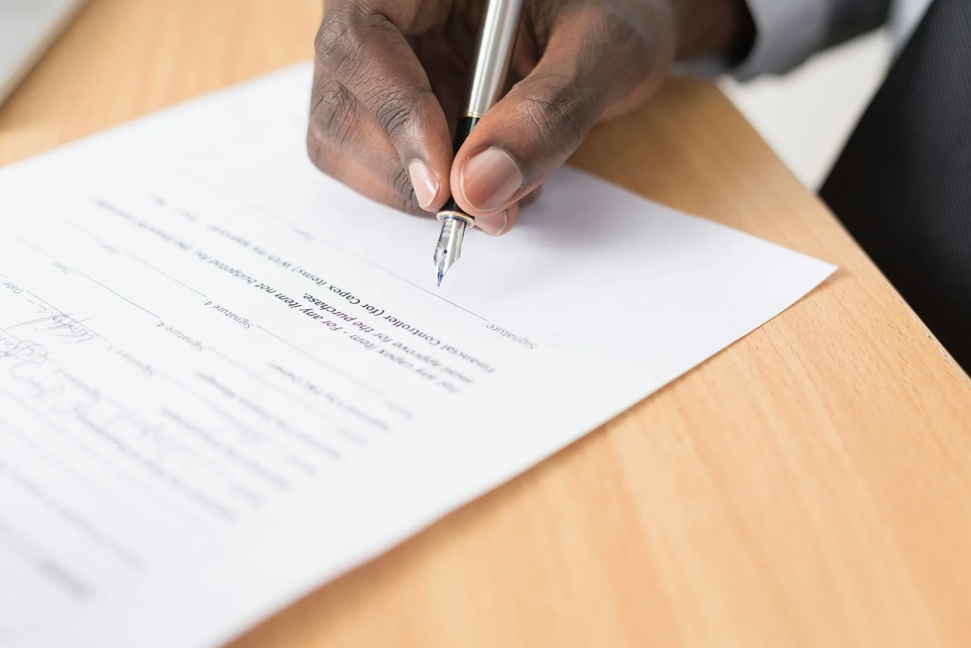 Hand signing a form with a pen